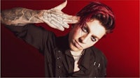 a man with red hair and tattoos posing for a photo